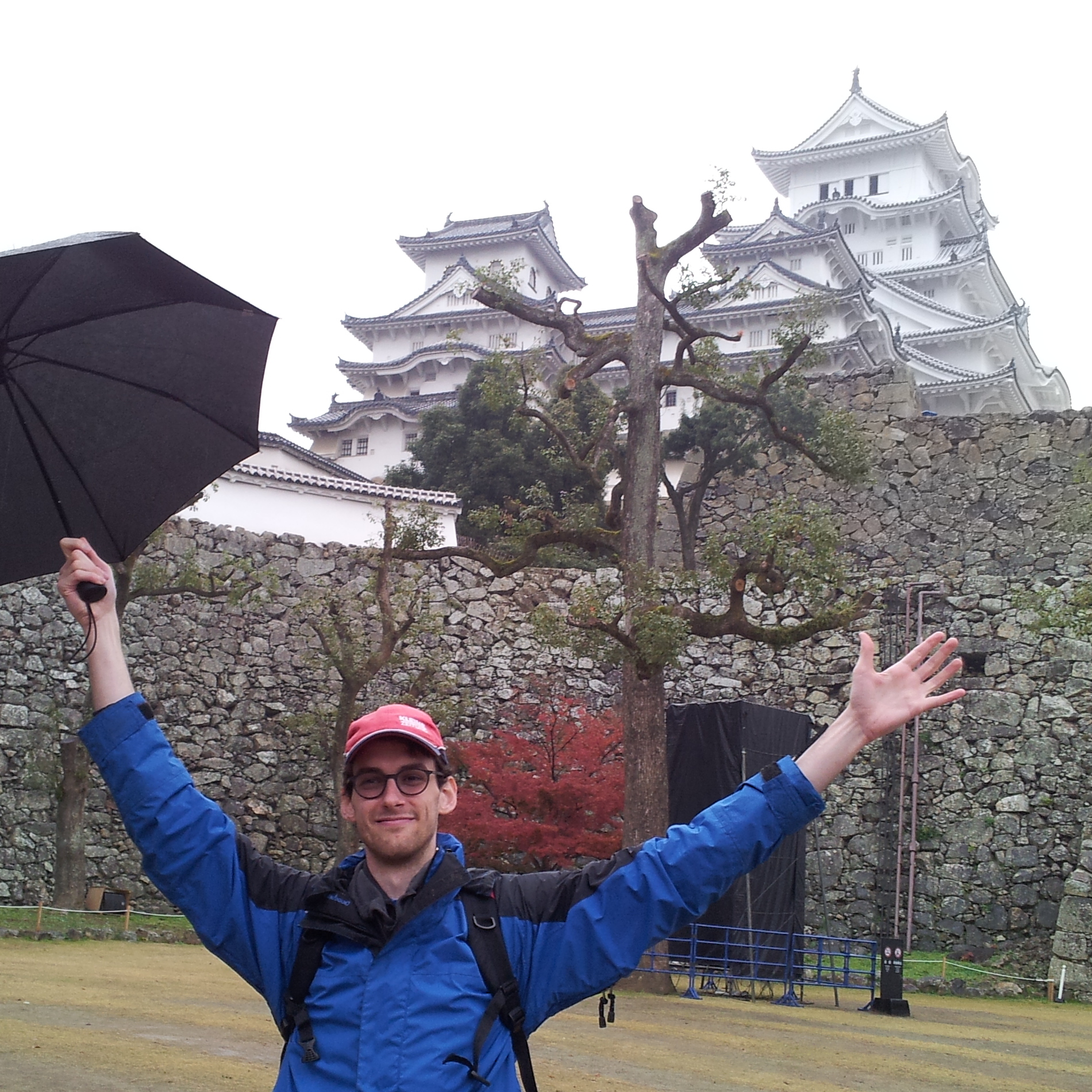 Lukas in foreground with an umbrella and Himeji Castle in the background