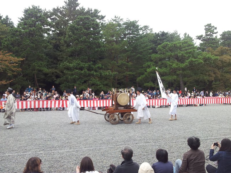 People in costumes pushing a wagon with a drum on it